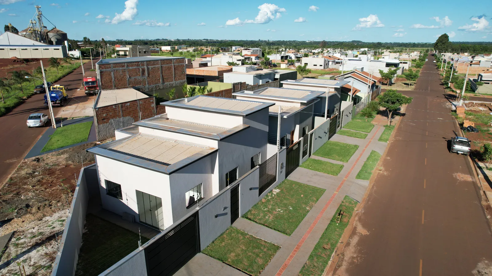 Rua asfaltada do Jardim Ibirapuera em Dourados/MS com casas construídas, calçada e meio-fio