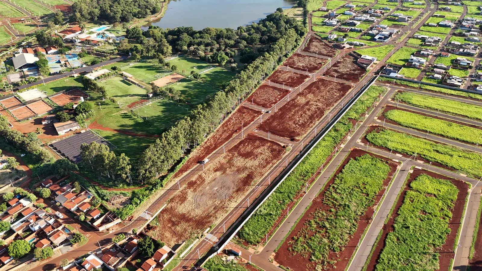 Vista aérea do Ouro Branco Loteamento Aberto em Dourados/MS ao lado do Clube Indaiá, com o lago, os campos e as quadras do clube visíveis